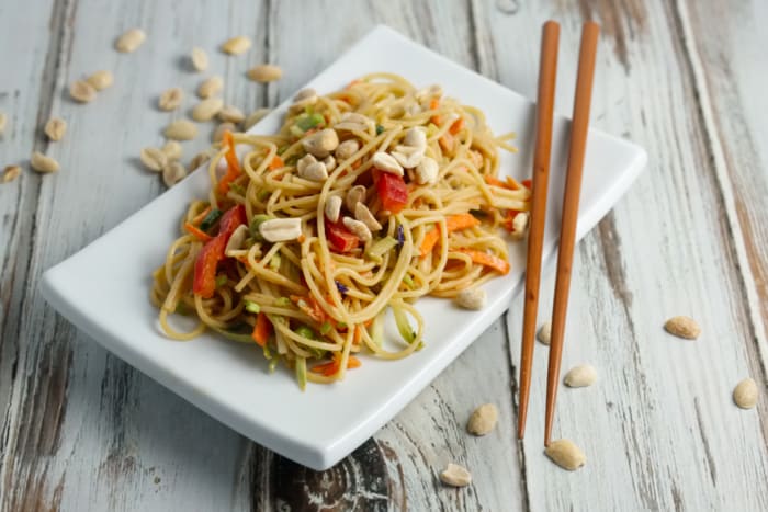A cold asian noodle salad on a white plate with chopsticks.